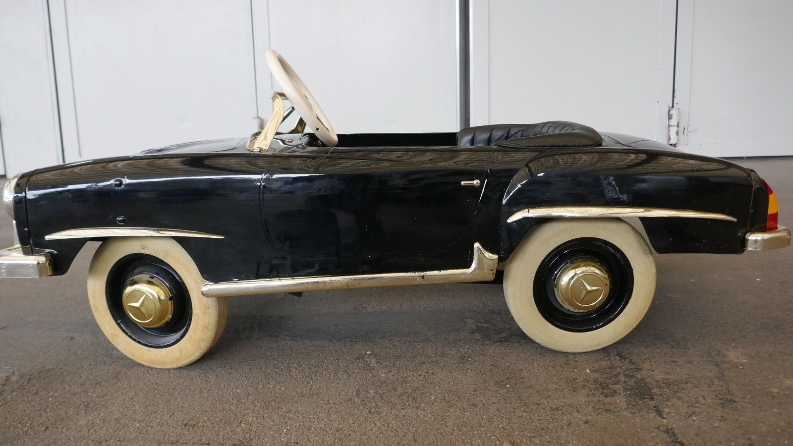 Ein schwarz-goldenes Tretauto mit weißen Reifen